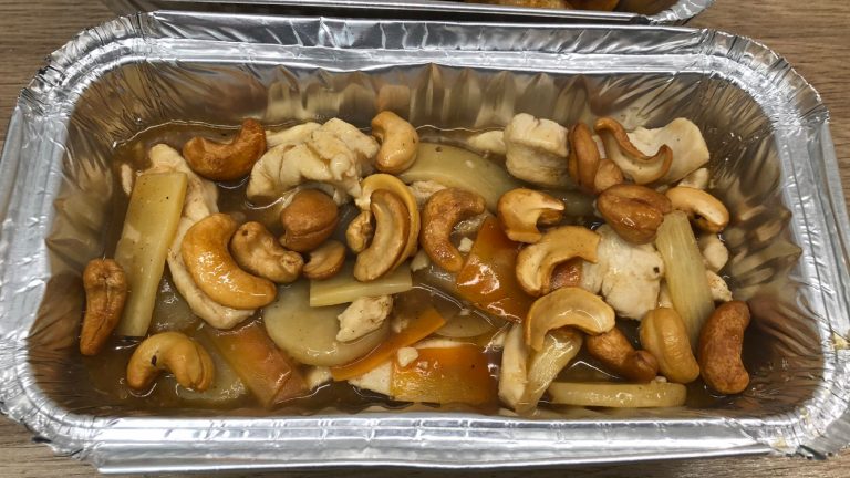 Chinese takeaway style chicken with cashew nuts in a foil container.
