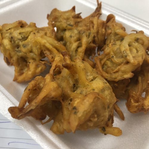Indian takeaway style onion bhajis in a food container.