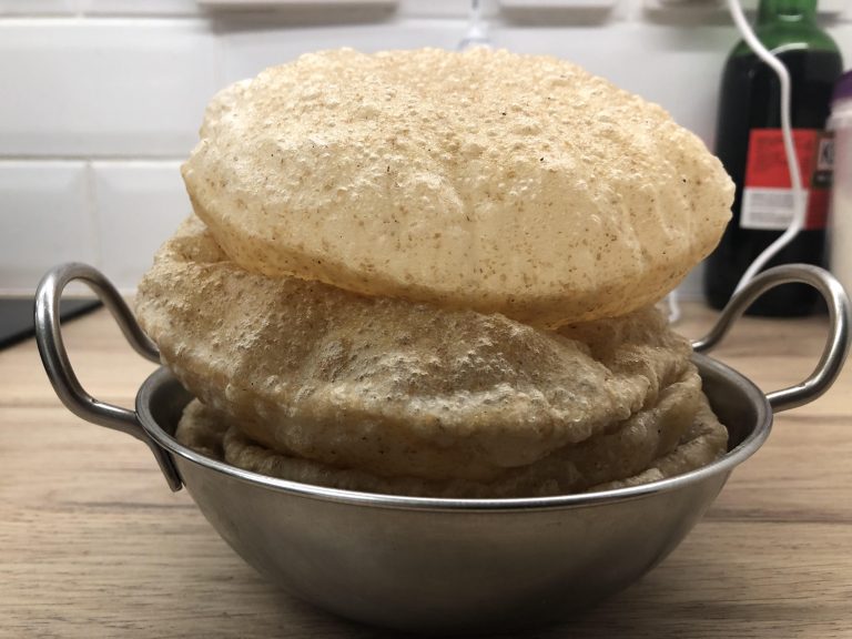 Fried puri breads in a serving bowl.