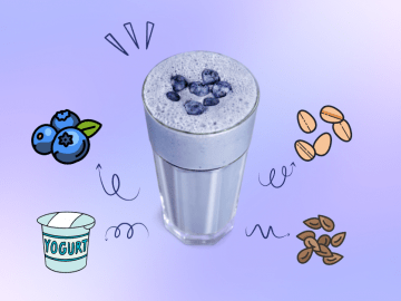A blueberry smoothie in a tall serving glass.