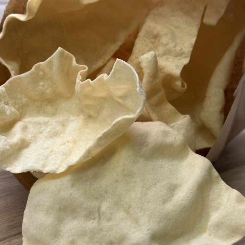 Freshly fried Indian restaurant style poppadoms in a paper bag.