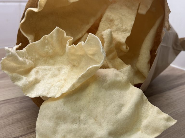 Freshly fried Indian restaurant style poppadoms in a paper bag.