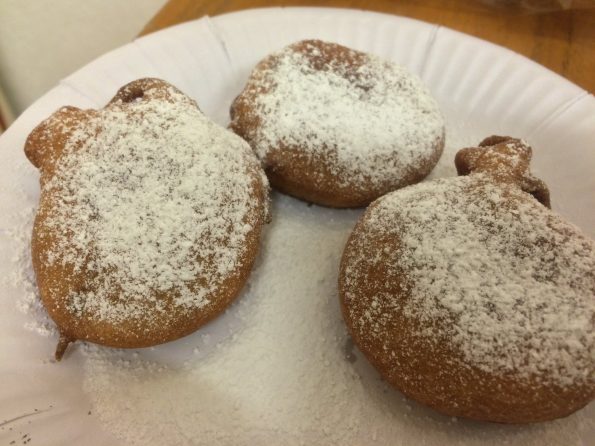 Deep Fried Oreos dusted with icing sugar and on a paper serving plate.