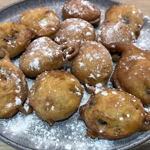 Deep fried cookies & cream biscuits dusted with icing sugar on a serving plate.