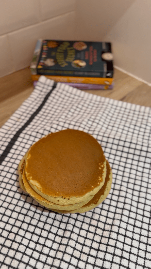 Cooked pancakes stacked on a tea towel.
