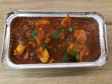 Chicken patia curry in a takeaway style foil container.
