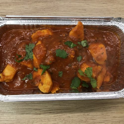 Chicken patia curry in a takeaway style foil container.