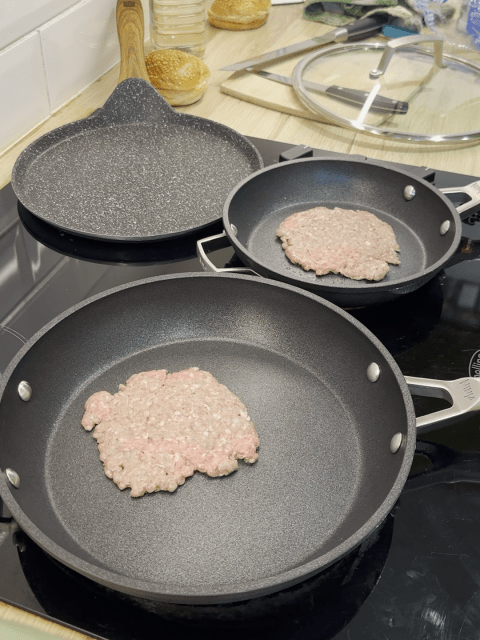 Minced beef smashed into burger patties in frying pans.