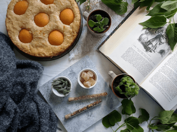 A tabletop with cooking ingredients laid out and a well used cookbook open at the correct page.