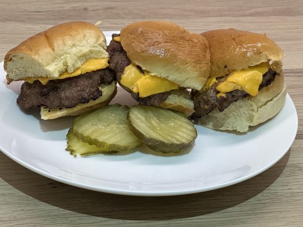 American fast food style sliders on a serving plate with gherkins.